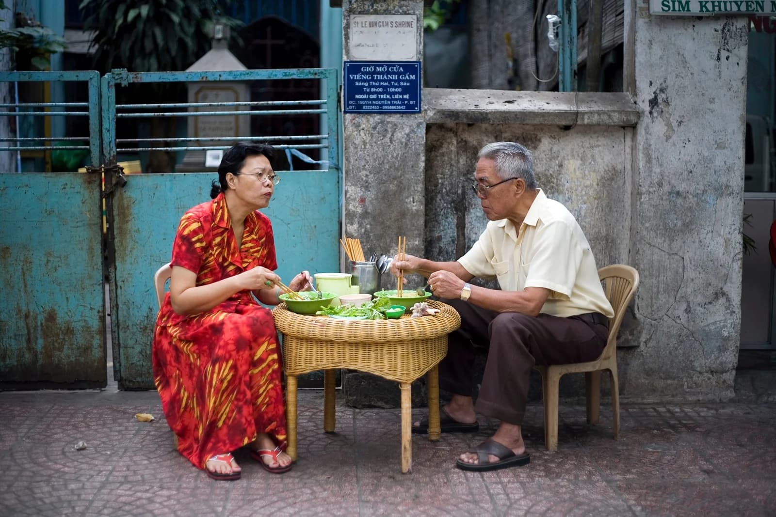 Two people eating breakfast at a street-side table in Ho Chi Minh City